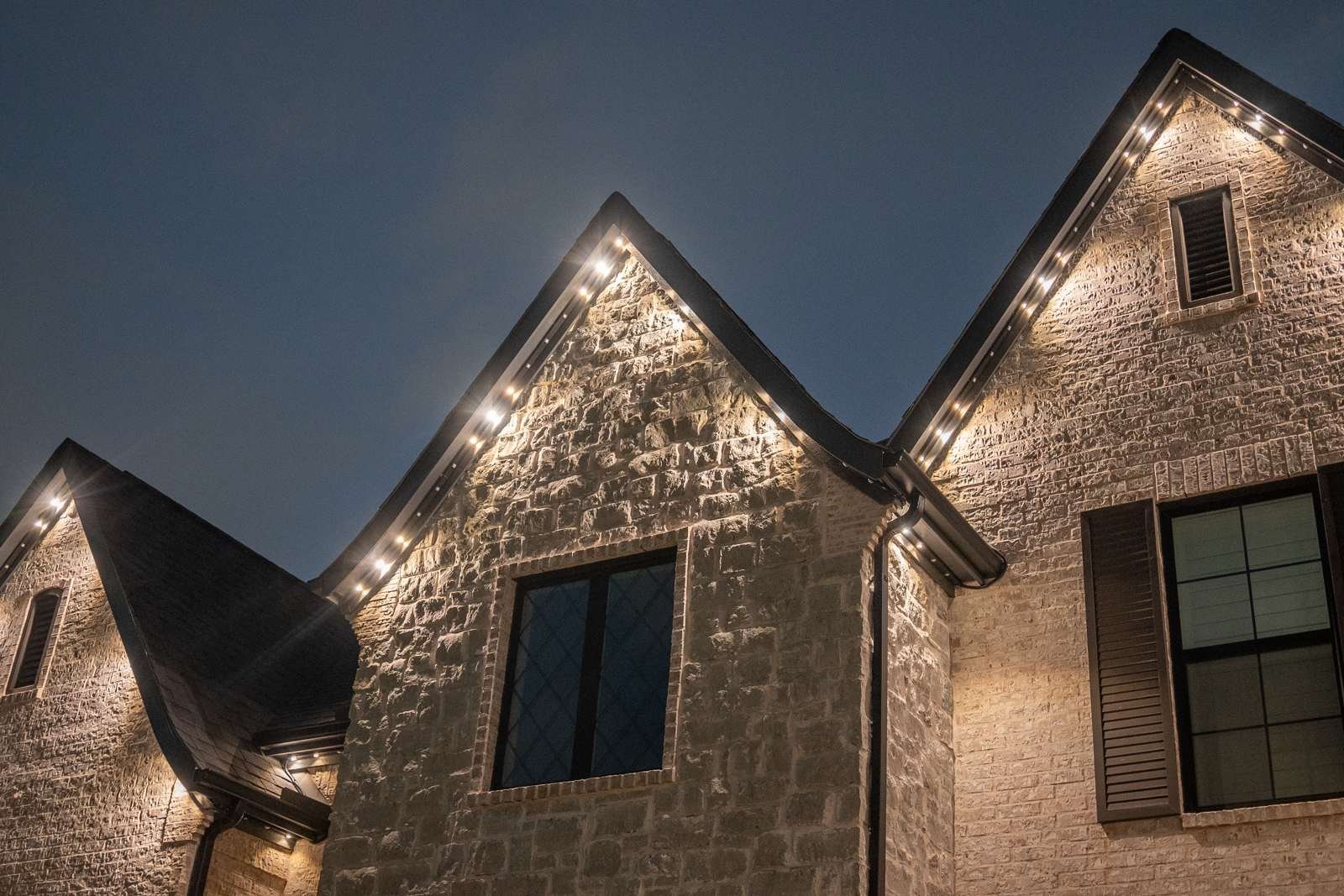 Close-up of warm white permanent lighting tracing a stone gable